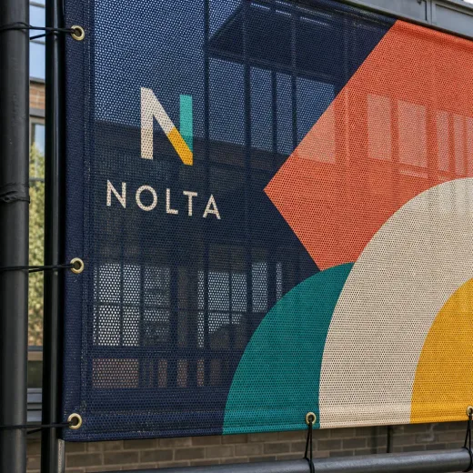 Perforated mesh banner installed as a building wrap with large-format graphics